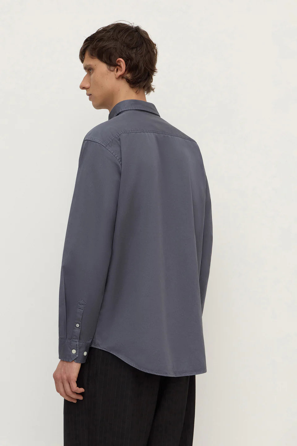 Person wearing a gray shirt and black pants on a white background