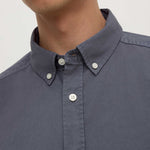 Close-up of a person wearing a dark blue button-up shirt with a plain background