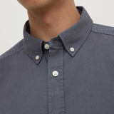 Close-up of a person wearing a dark blue button-up shirt with a plain background