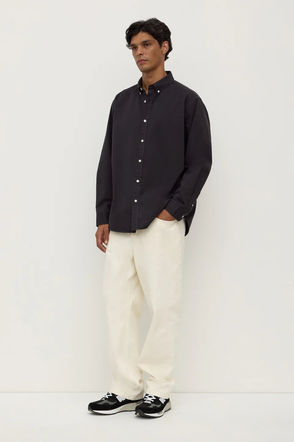 Man wearing a black shirt and white pants on a white background