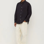 Man wearing a black shirt and white pants on a white background