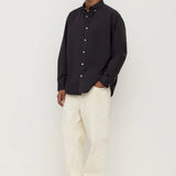 Man wearing a black shirt and white pants on a white background