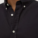 Close-up of a black button-up shirt with white buttons on a neutral background