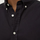 Close-up of a black button-up shirt with white buttons on a neutral background