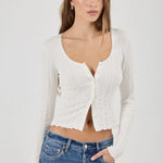 Woman wearing a white textured Top and blue jeans on a plain background