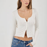 Woman wearing a white textured Top and blue jeans on a plain background