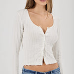 Woman wearing a white textured Top and blue jeans on a plain background
