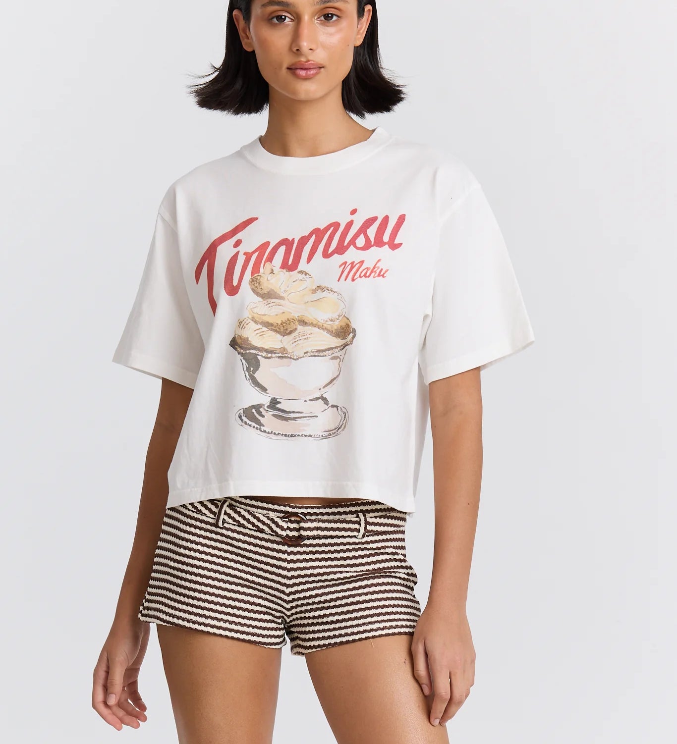 Woman wearing a white t-shirt with a dessert graphic and 'Tiramisu Maku' text on a plain background
