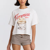 Woman wearing a white t-shirt with a dessert graphic and 'Tiramisu Maku' text on a plain background