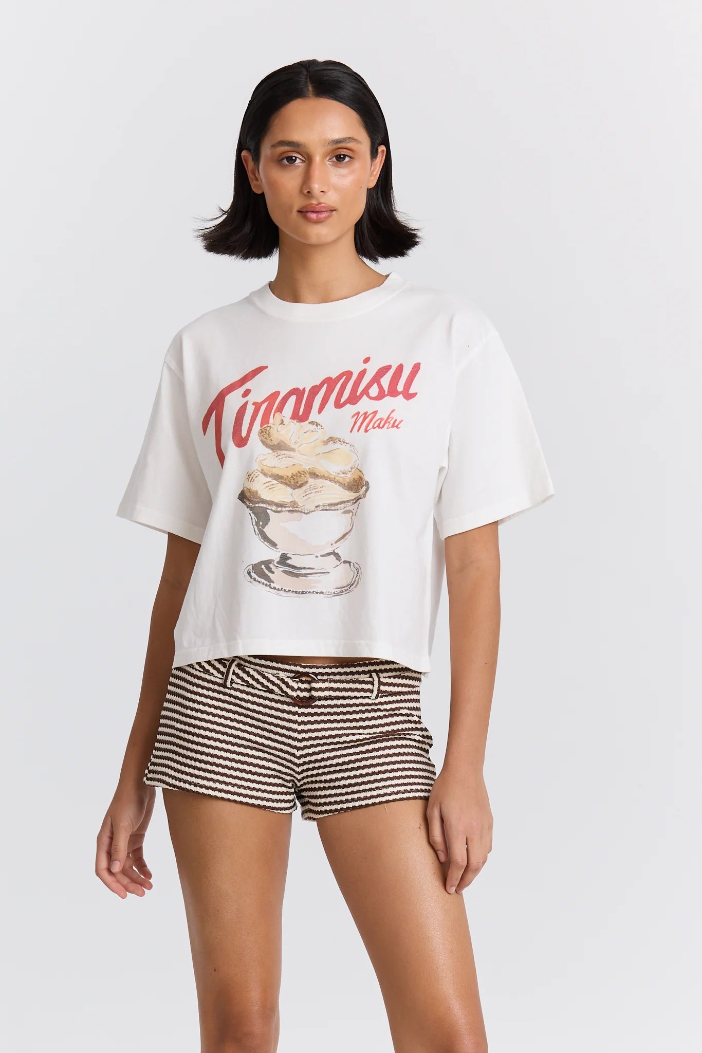 Woman wearing a white t-shirt with a dessert graphic and 'Tiramisu Maku' text on a plain background