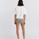 Person wearing a white top and striped shorts on a plain background