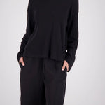 A model wearing a black long-sleeve top and matching black shorts with side pockets, photographed against a light gray studio background.