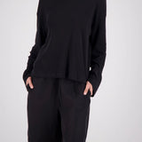 A model wearing a black long-sleeve top and matching black shorts with side pockets, photographed against a light gray studio background.