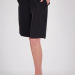 A person wearing black drawstring shorts with side pockets, paired with black sandals, shown from the waist down against a light gray studio background.