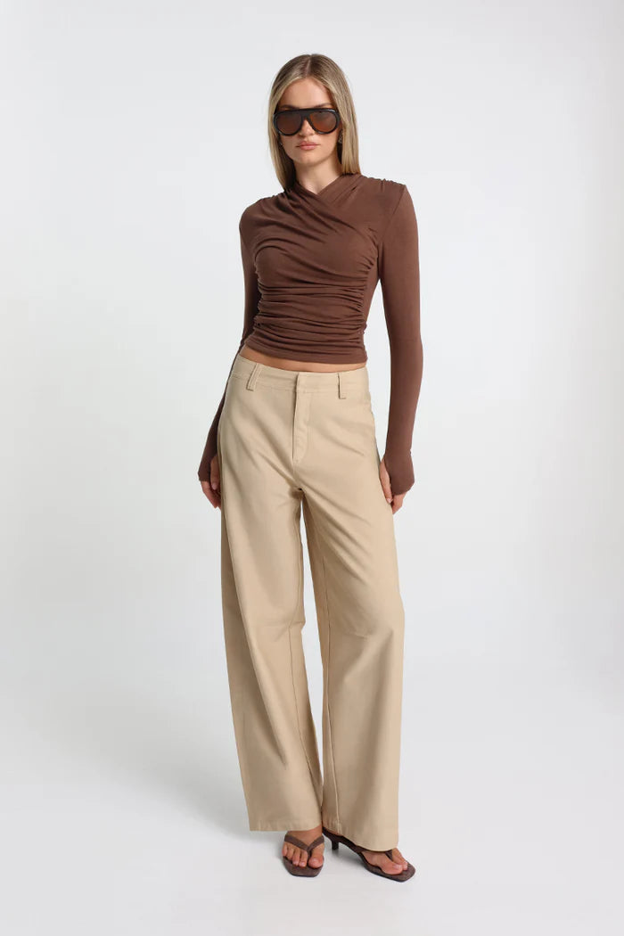 Woman wearing a brown top and beige pants on a white background