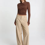 Woman wearing a brown top and beige pants on a white background
