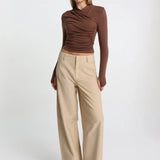 Woman wearing a brown top and beige pants on a white background