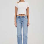 Woman wearing a white t-shirt and light blue jeans on a plain background