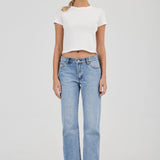 Woman wearing a white t-shirt and light blue jeans on a plain background