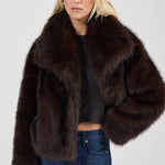 Woman wearing a brown fur coat on a plain background