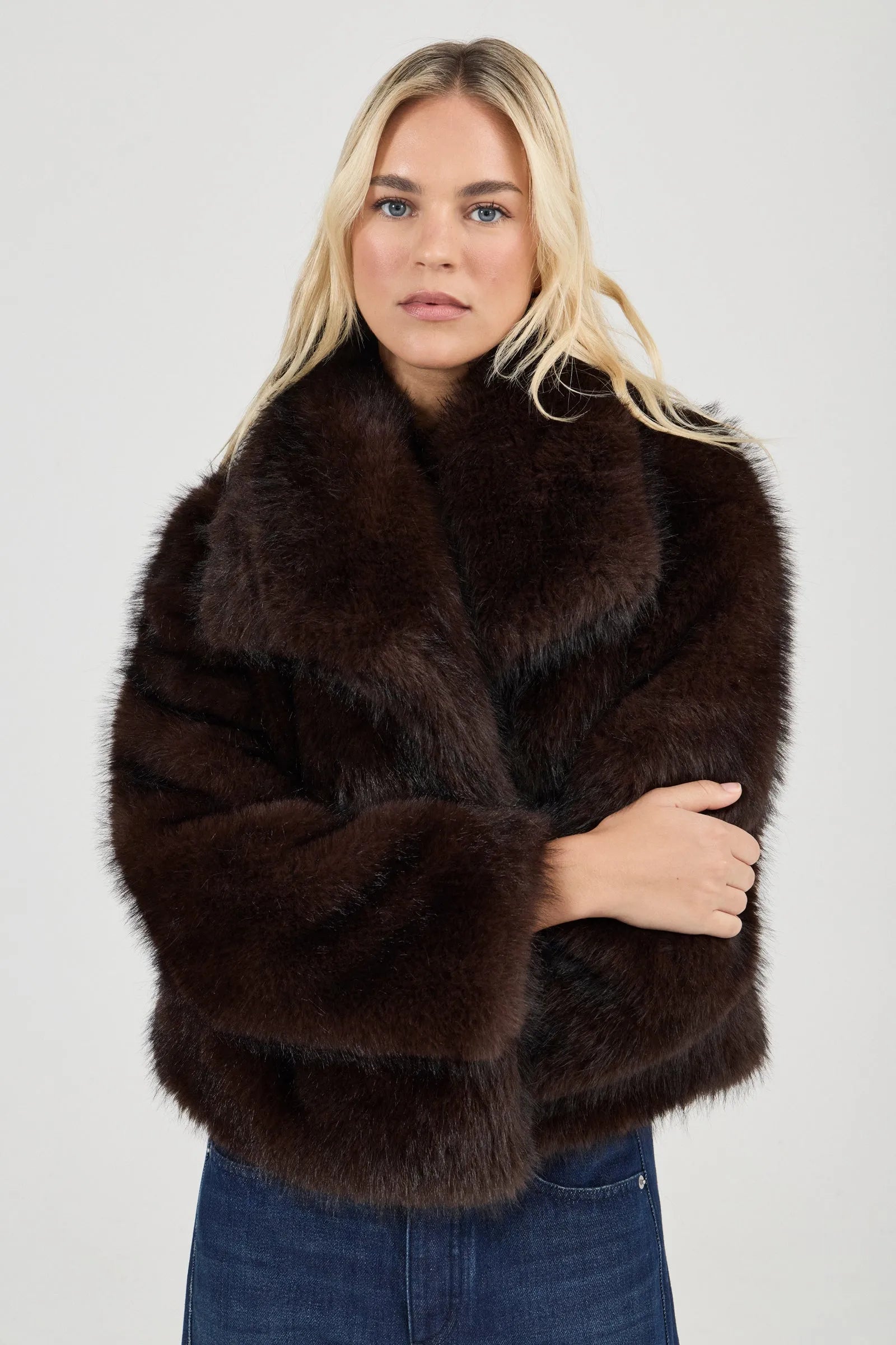 Woman wearing a dark brown fur coat against a plain background