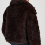 Person wearing a brown fur jacket on a plain background