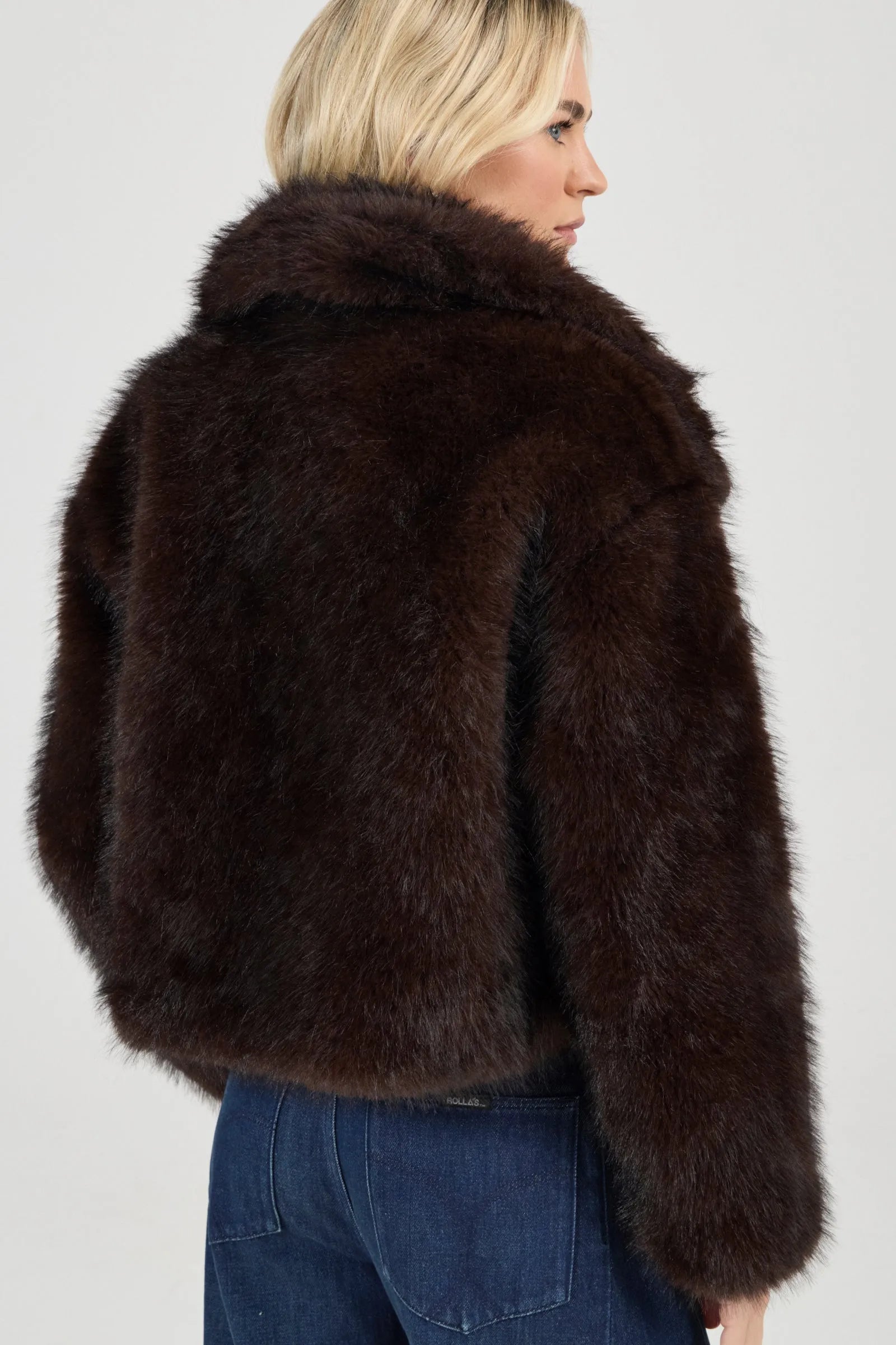 Person wearing a brown fur jacket on a plain background