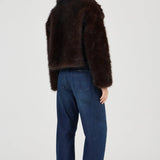 Woman wearing a brown fur coat and blue jeans on a white background