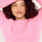 Person wearing a pink fuzzy sweater with a white background