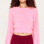 Person wearing a pink sweater and burgundy pants on a white background