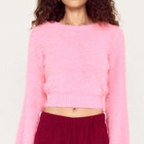 Person wearing a pink sweater and burgundy pants on a white background