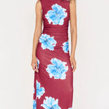 Woman wearing a burgundy dress with blue floral patterns on a white background