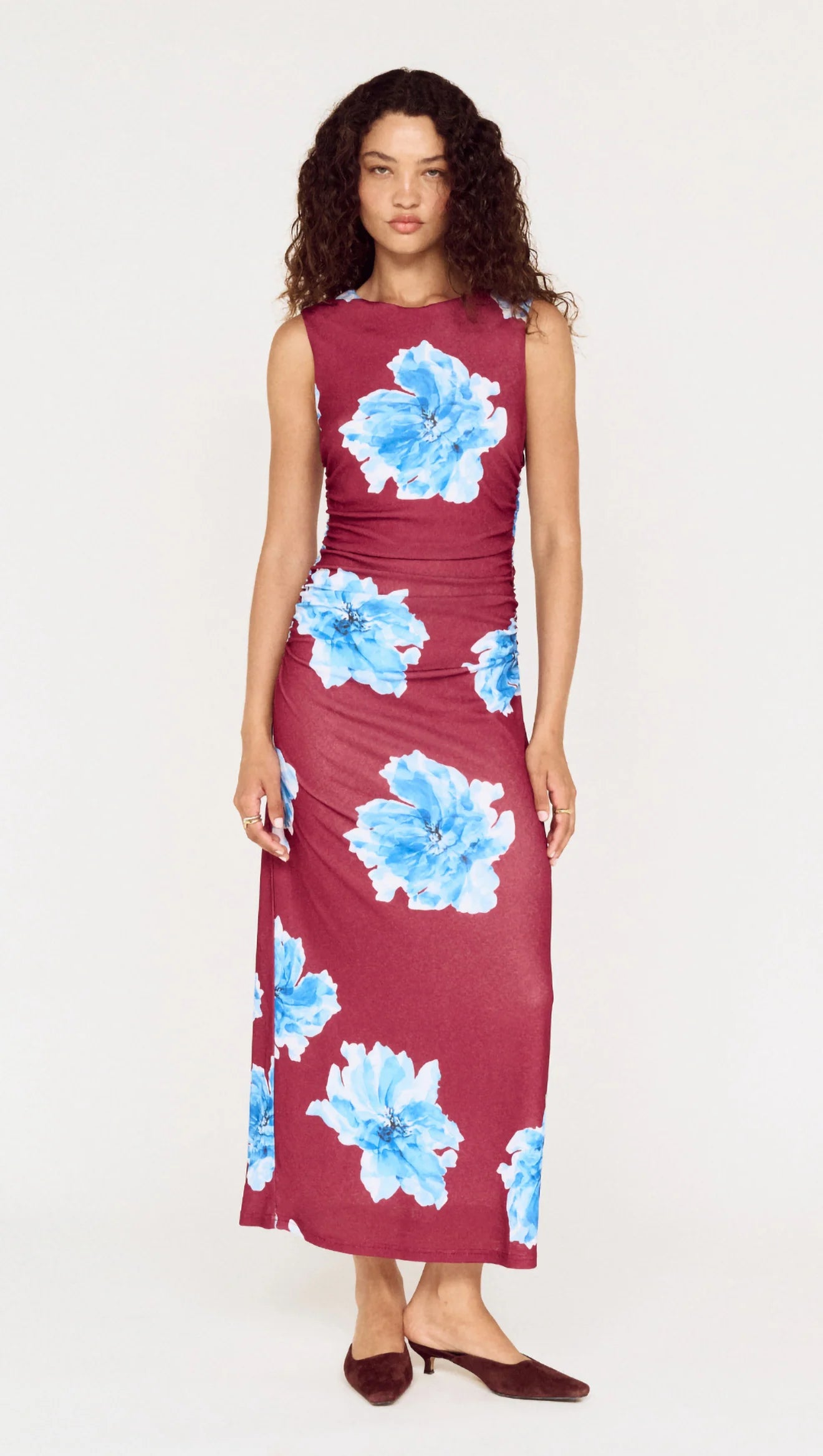 Woman wearing a burgundy dress with blue floral patterns on a white background
