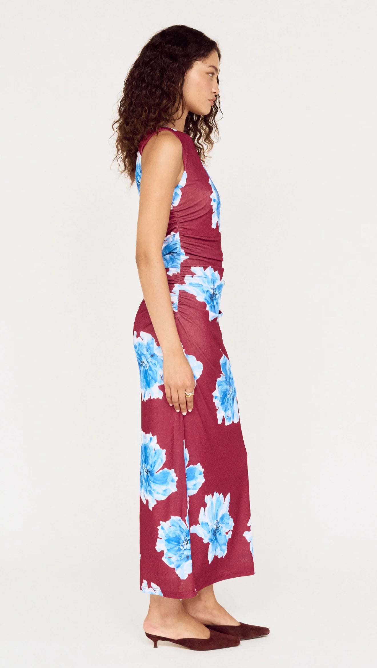 Woman wearing a burgundy dress with blue floral pattern on a white background
