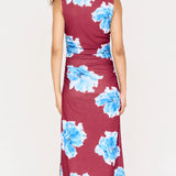 Woman wearing a sleeveless dress with blue floral pattern on a white background