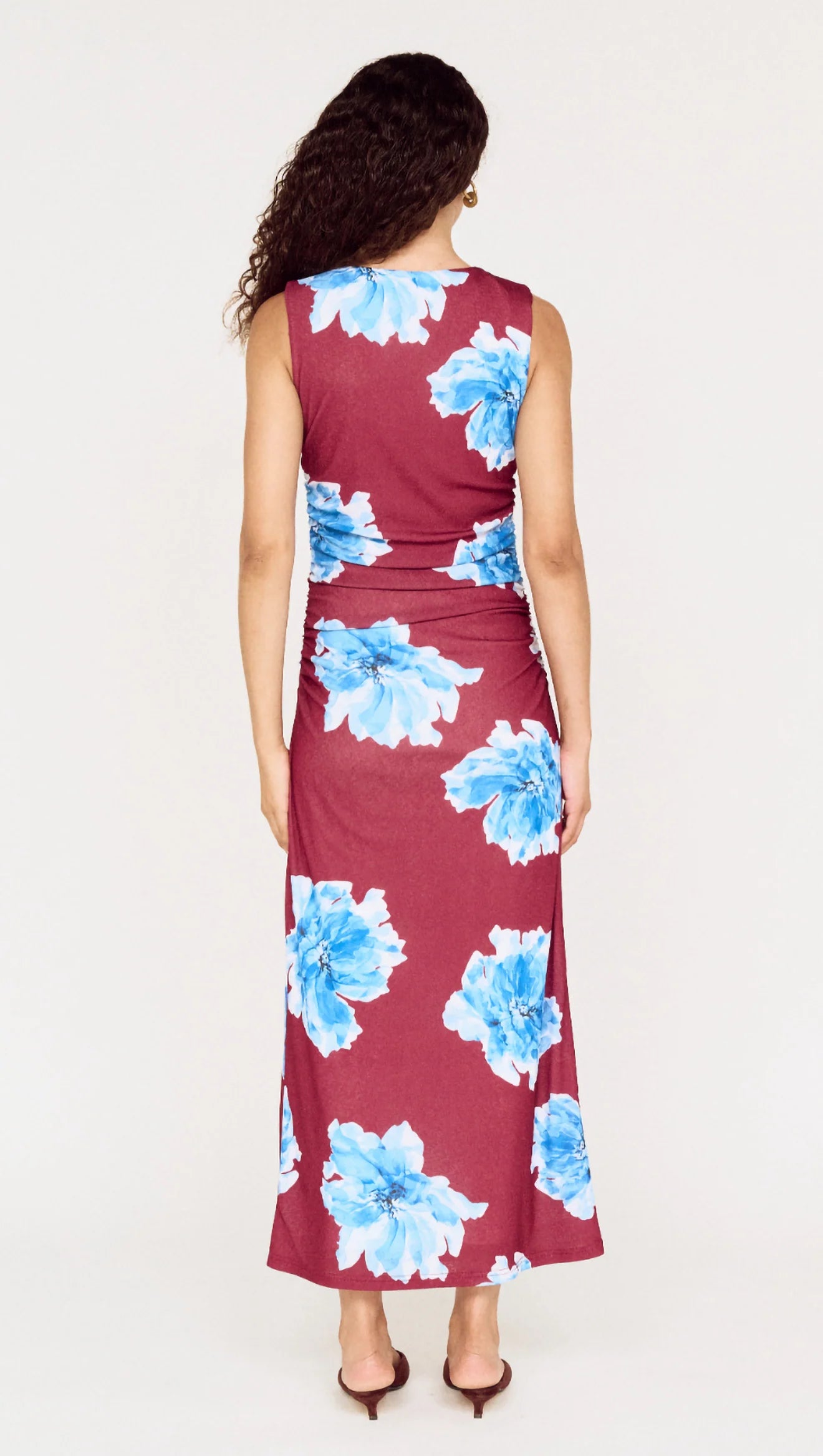 Woman wearing a sleeveless dress with blue floral pattern on a white background