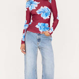 Woman wearing a floral top and jeans on a white background