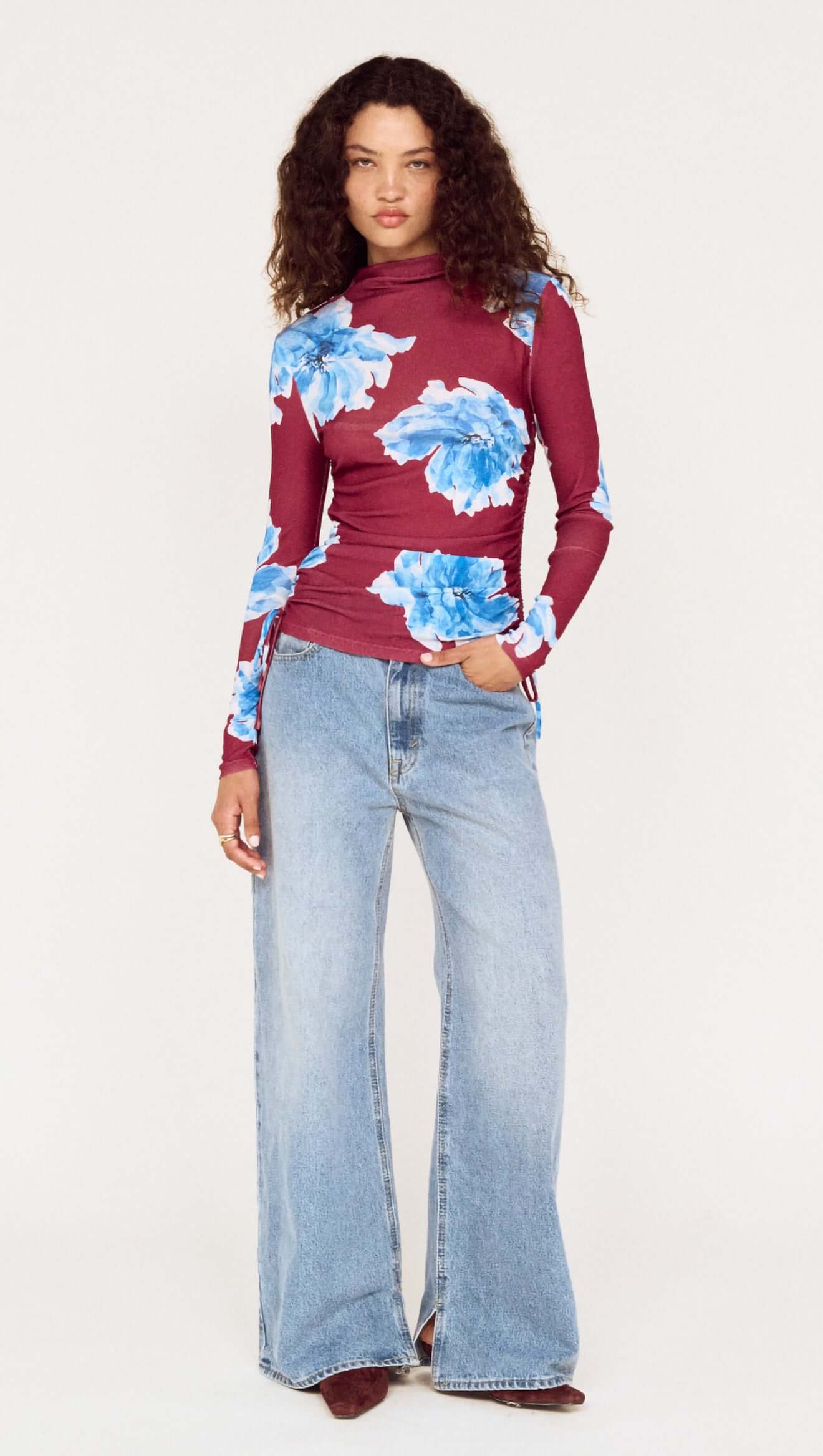 Woman wearing a floral top and jeans on a white background