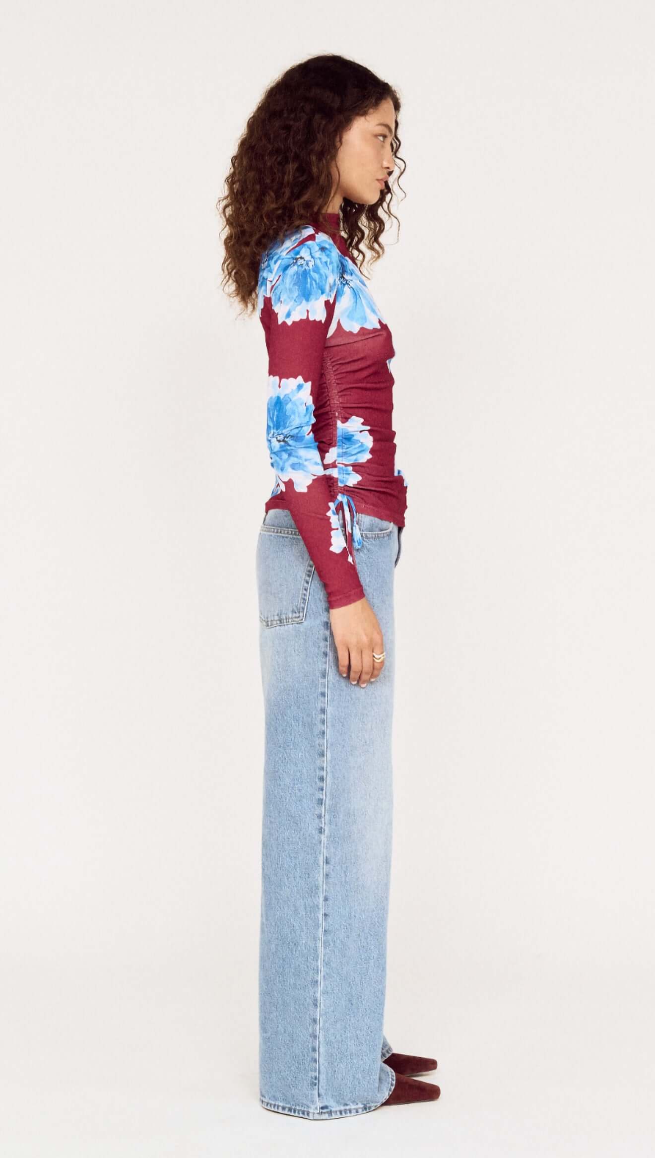 Person wearing a red and blue floral jacket with light blue jeans on a white background