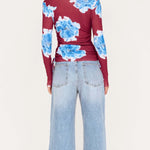 Person wearing a red floral top and light blue jeans on a white background