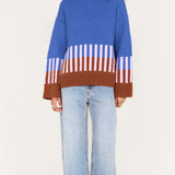 Person wearing a blue sweater with a striped pattern and light blue jeans on a white background
