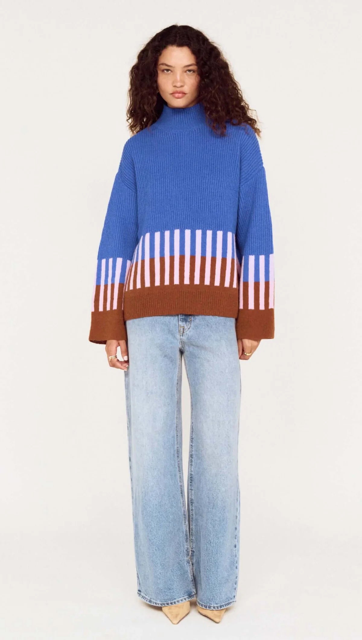 Person wearing a blue sweater with a striped pattern and light blue jeans on a white background