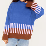 Person wearing a colorful striped sweater with a plain background