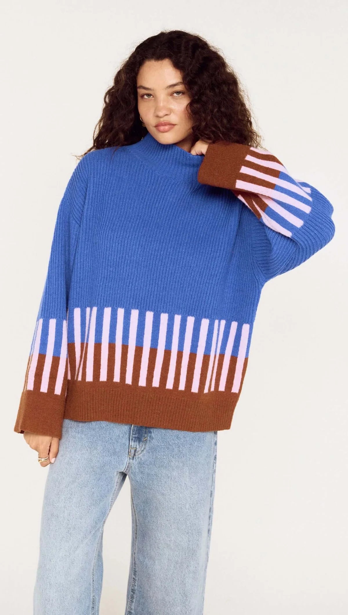 Person wearing a colorful striped sweater with a plain background