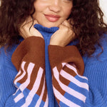 Person wearing a blue sweater with brown and white striped sleeves against a white background
