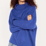 Woman wearing a blue sweater over a floral dress on a white background
