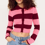 Person wearing a pink and purple striped cardigan with blue jeans on a white background