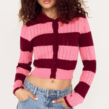 Person wearing a pink and purple striped cardigan with blue jeans on a white background