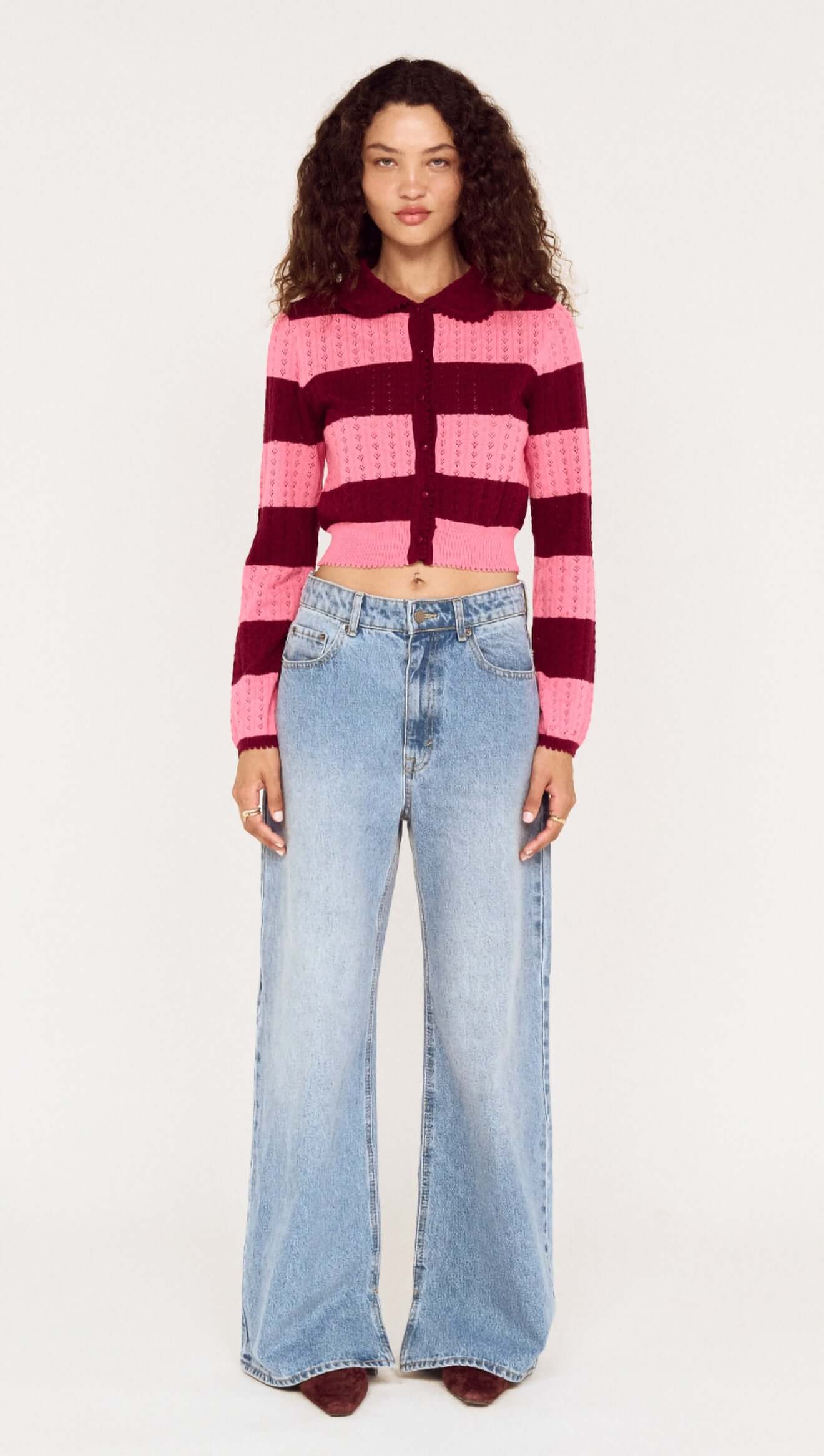 Person wearing a striped sweater and jeans on a white background