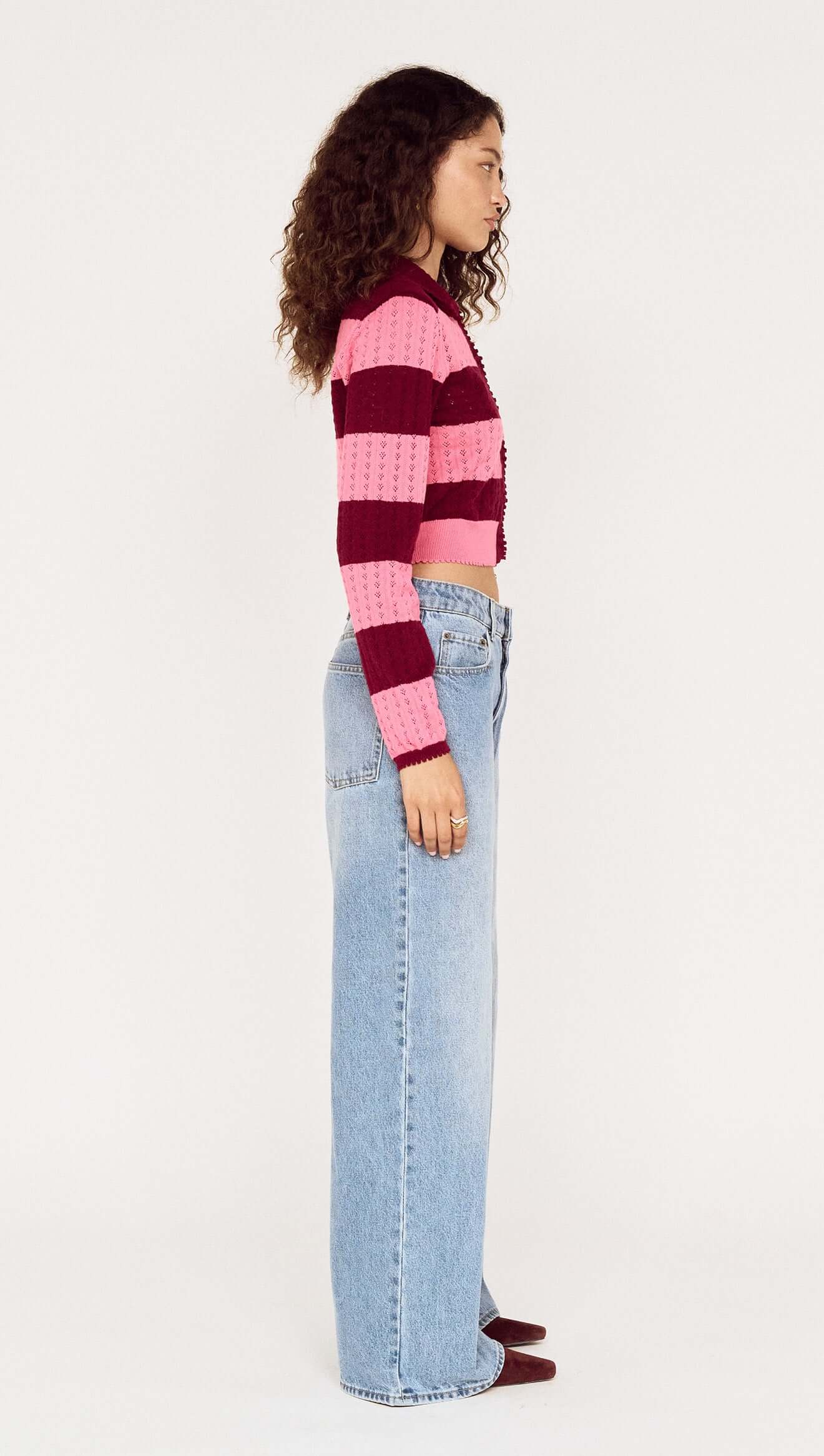 Person wearing a striped sweater and jeans on a white background